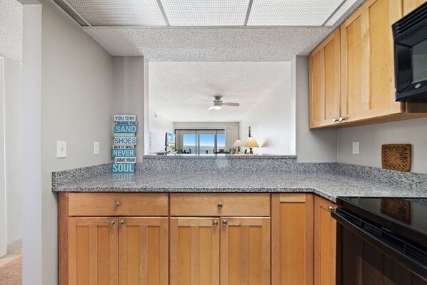 A kitchen with wooden cabinets, a granite countertop, and a ceiling fan.
