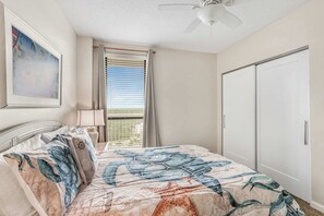 A hotel room with a bed, a ceiling fan, a window with curtains, and a door. - Pelican Pointe1204: 3BR/ 2BA, gulf-front. (Orange Beach)