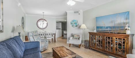 Un salon avec un canapé bleu, une table basse en bois, un fauteuil blanc et un meuble en bois doté de portes en verre.