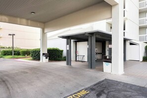 A covered parking area with a trash bin labeled "HOUSEHOLD TRASH" and a "ZONE" marking on the ground. - Pelican Pointe1204: 3BR/ 2BA, gulf-front. (Orange Beach)