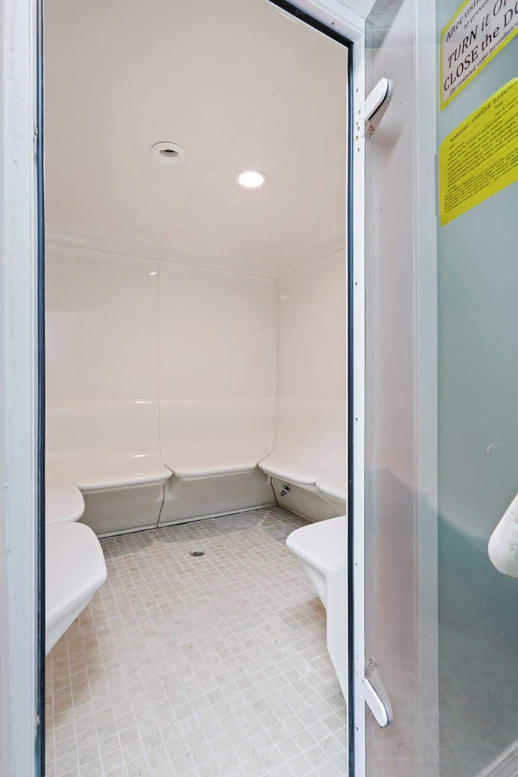 A small, enclosed bathroom with a tiled floor, a toilet, and a sink.