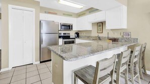 A kitchen with white cabinets, stainless steel appliances, and a granite countertop.