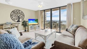 A living room with a TV, a sofa, a coffee table, and a balcony with a view.