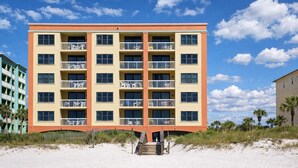 A multi-story hotel with balconies, located on a sandy beach with palm trees. - Harbour Place 102-  gulf-view, out & indoor pool, hot tub (Orange Beach)