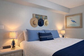 A neatly arranged bedroom with a bed, two bedside tables, and a wall-mounted hat display.