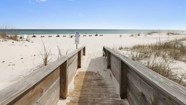 A wooden boardwalk leading to a sandy beach with a clear sky. - Palm Beach 22-D, beachfront, beach-view, 2nd floor (Orange Beach)