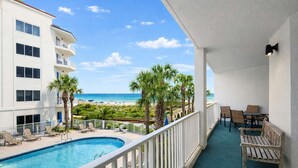 A balcony with a pool, lounge chairs, and a view of the beach and ocean. - Palm Beach 22-D, beachfront, beach-view, 2nd floor (Orange Beach)