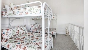 A bunk bed room with a white ceiling fan, a decorative bird sculpture, and a white railing.