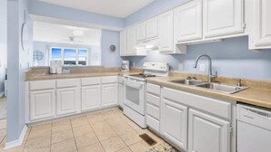 A kitchen with white cabinets, a stove, a sink, and a window.