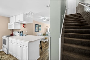 A modern kitchen with white cabinetry, a central island, and a dining area with a table and chairs.