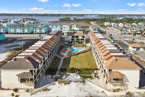 Ein Hotel an der Küste mit mehrstöckigen Gebäuden, einem zentralen Innenhof mit Pool und Blick auf den Strand und das Meer.