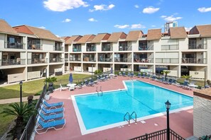 Un hotel con piscina, varios balcones y zonas de estar al aire libre.