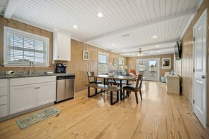 A kitchen with wooden cabinets, a dining area with a table and chairs, and a view of the outside. - Don't Worry, Beach Happy; 6 BR, 4 BA, sleeps 20. (Gulf Shores)