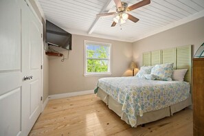 A bedroom with a bed, a ceiling fan, a window, and a TV mounted on the wall. - Don't Worry, Beach Happy; 6 BR, 4 BA, sleeps 20. (Gulf Shores)