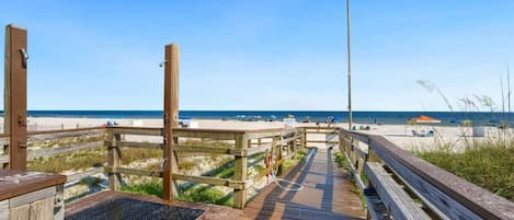 A wooden boardwalk leading to a beach with clear skies.