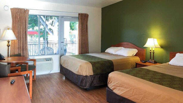 Habitación de hotel con dos camas, un escritorio y una silla.