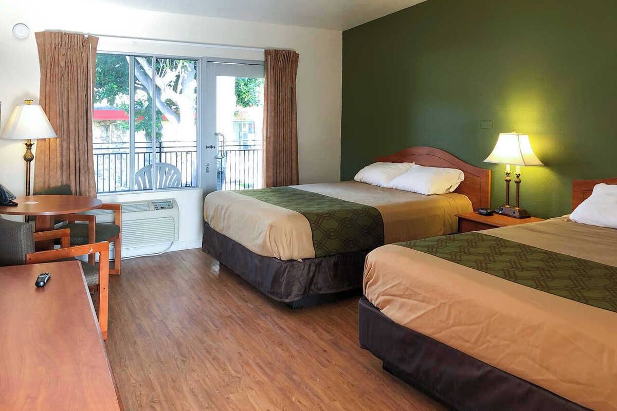 Habitación de hotel con dos camas, un escritorio y una silla.
