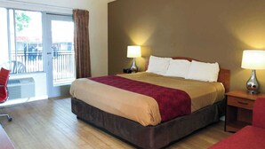 Habitación de hotel con una cama grande, dos lámparas de noche, un escritorio de madera, una silla y un balcón con vistas.