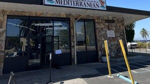 Un edificio con un letrero que dice "PALMS MEDITERRANEAN" y fachada de piedra.