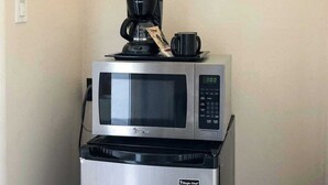 Una cocina con microondas y cafetera sobre un refrigerador.