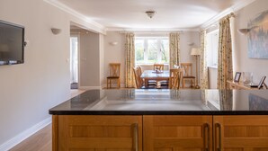 A modern kitchen with wooden cabinets, a large island, and a dining area with a table and chairs. - Cunsey Lodge with Woodfired Hot Tub and stunning views (Cunsey)