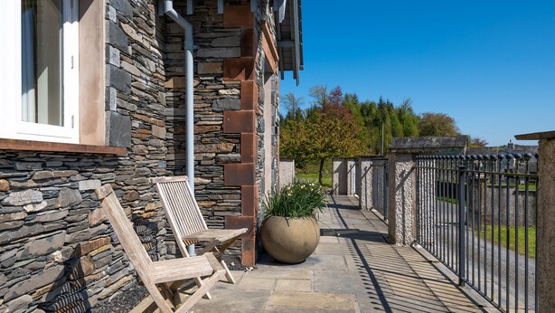 A stone building with a balcony, a large planter, and a metal fence. - Cunsey Lodge with Woodfired Hot Tub and stunning views (Cunsey)