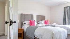 A hotel room with two beds, a wooden nightstand, and a door. - Eel House Cottage - sleeps 4 guests  in 2 bedrooms (Graythwaite)
