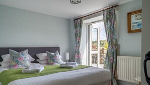 Een slaapkamer met een groot bed, bloemen gordijnen en uitzicht op de omgeving.