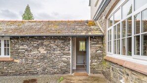 A stone building with a sloped roof and a door leading to an interior space.