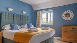 A bedroom with a large bed, a wooden dresser, and a window with curtains.