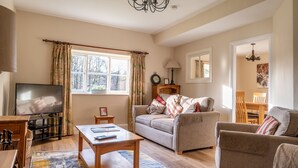 A cozy living room with a sofa, armchairs, a coffee table, and a TV. - Jubilee - sleeps 6 guests  in 3 bedrooms (Graythwaite)