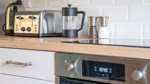 A kitchen with a coffee maker, salt and pepper shakers, a toaster, and an oven with a digital clock displaying 1040. - Jubilee - sleeps 6 guests  in 3 bedrooms (Graythwaite)