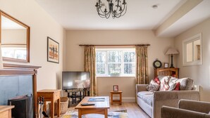 A living room with a fireplace, television, sofa, and a chandelier. - Jubilee - sleeps 6 guests  in 3 bedrooms (Graythwaite)