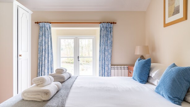 A hotel room with a bed, a window with curtains, a radiator, and a lamp. - Jubilee - sleeps 6 guests  in 3 bedrooms (Graythwaite)