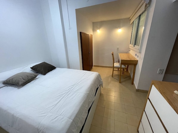 A bedroom with a bed, a desk, and a chair.