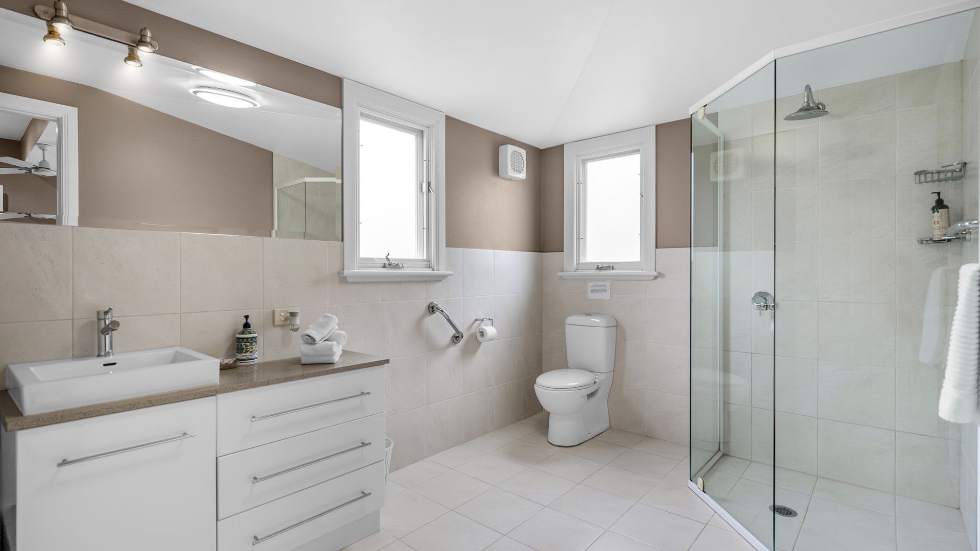 A modern bathroom with a glass-enclosed shower, a sink with a vanity, and a toilet.