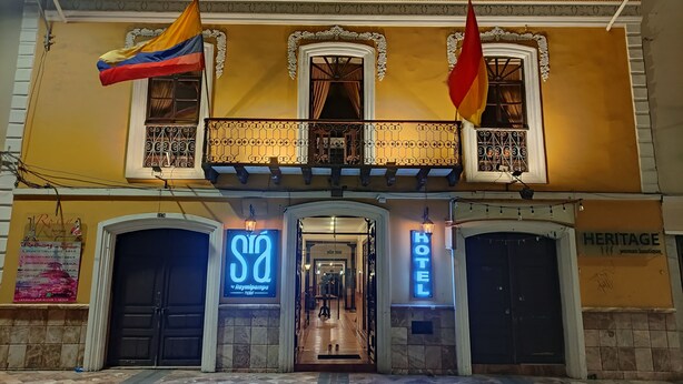 A hotel facade with two flags, a sign for 'Hotel Raymipampa', and a 'Heritage' boutique. - SÁ Hotel (Cuenca)