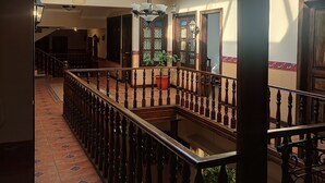 A spacious corridor with a wooden railing, a tiled floor, and a glass ceiling allowing natural light. - SÁ Hotel (Cuenca)