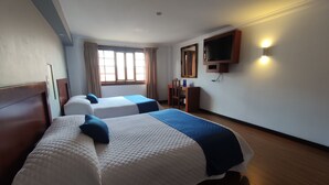 A hotel room with two beds, a desk, a chair, a TV mounted on the wall, and a window with curtains. - SÁ Hotel (Cuenca)