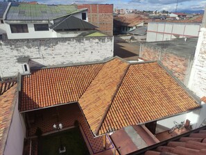 A rooftop with terracotta tiles, a small garden area with a bench, and a bicycle parked nearby. - SÁ Hotel (Cuenca)