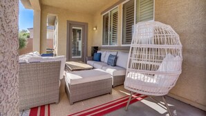 Un espace extérieur aménagé avec des meubles en osier, comprenant une chaise en osier blanche et un tapis rayé rouge et blanc.