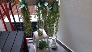 Un balcone con una pergola in legno, piante in vaso, un lanternino bianco e un tavolino.