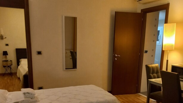 Una camera d'albergo con due letti, una scrivania, una sedia, un condizionatore d'aria e uno specchio.