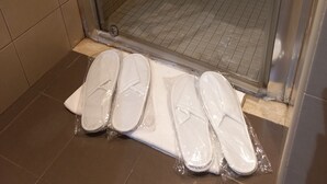 Un'area doccia con porta in vetro, pareti piastrellate e uno scarico sul pavimento.