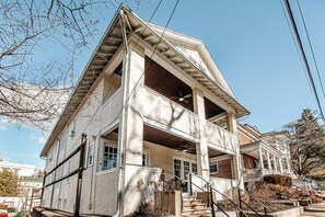 A two-story building with a balcony on the second floor, a covered porch, and a staircase leading to the entrance.