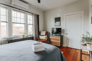 A bedroom with a large bed, a chair, a TV, and a door.