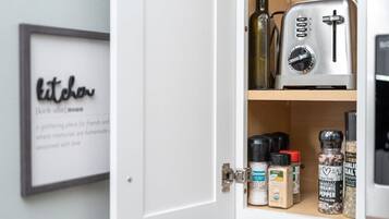 A kitchen cabinet with a toaster and various spices.