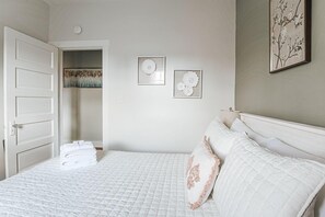 A bedroom with a bed, a closet, and two wall-mounted pictures.