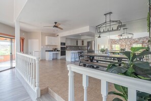 A spacious kitchen with white cabinets, a dining area with benches, and a stone accent wall. - NEW! Hidden mini movie theater, Game room, Putt putt, Pool, & MORE (Phoenix)