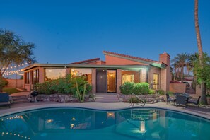 A modern house with a swimming pool, outdoor seating, and a well-maintained garden.